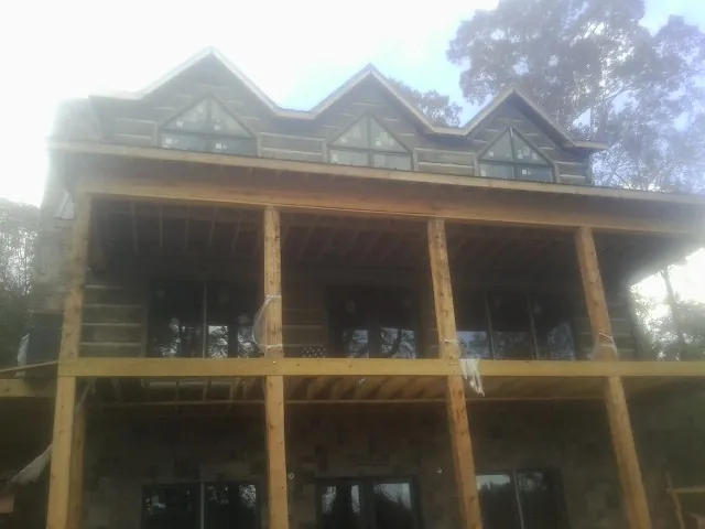 Dormers and porch framing on a large log home under construction — Roof Coating work by our crew in North Walpole