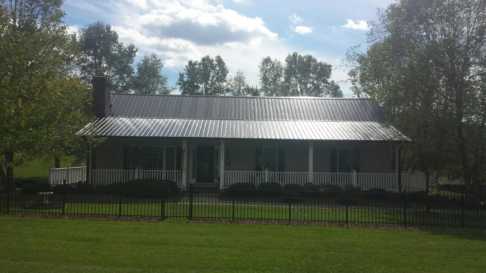 Gray metal roof on a brick ranch with a full width front porch — Gutter Guard Installation work by our crew in North Walpole