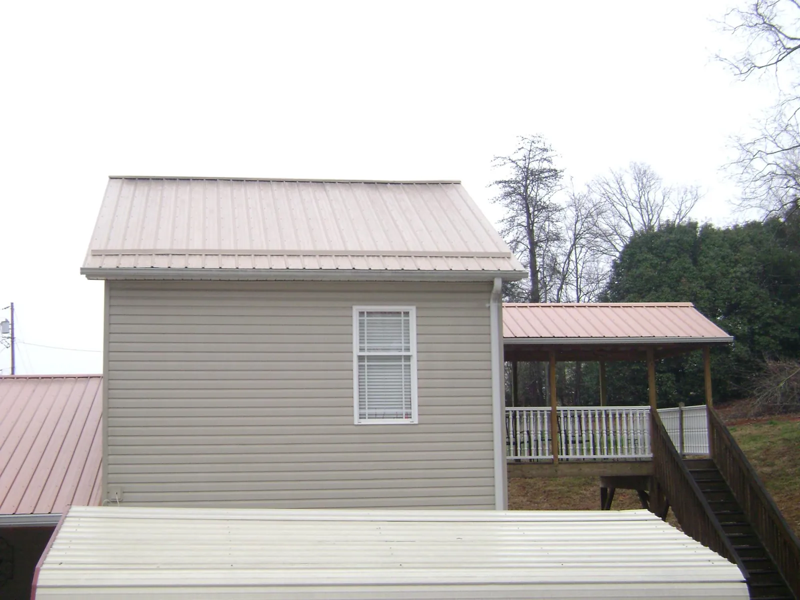 Tan metal roofs on a two story addition and attached porch, from a Roof Replacement job in North Walpole