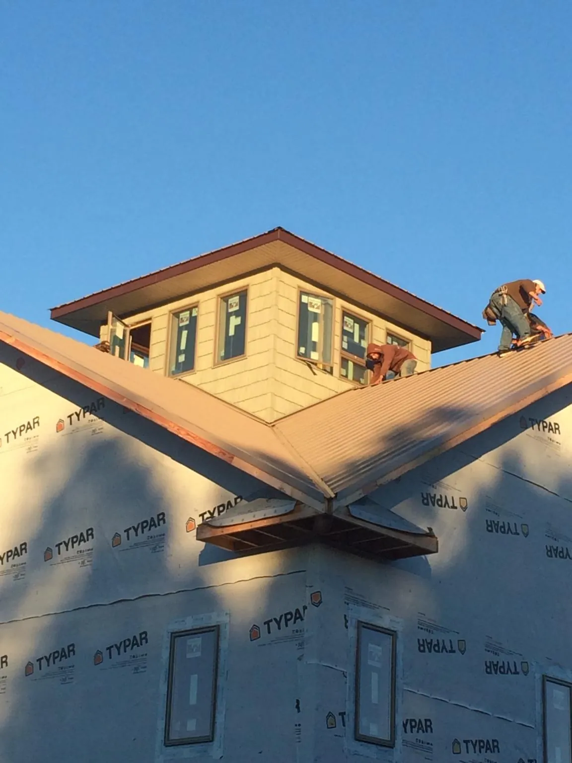 Roofers working around a rooftop cupola on a new metal roof at sunset — Roof Waterproofing in North Walpole by Roofing Brothers